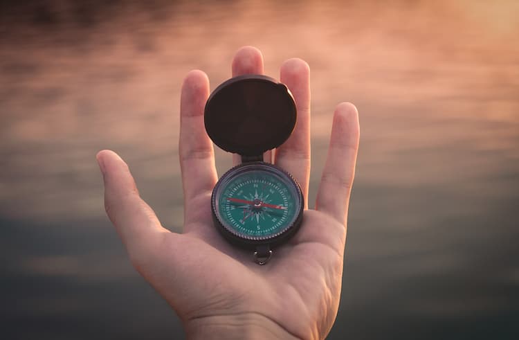 A hand holding a compass. 
